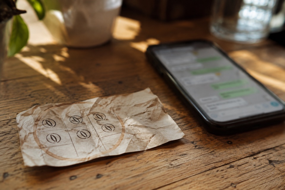 Verknitterte Papierstempelkarte neben einem Smartphone mit WhatsApp-Chat